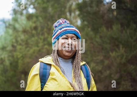 Happy african senior woman having fun during trekking day in to the wood - Focus on face Stock Photo