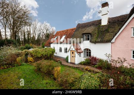 Kedington, Suffolk, November 19 2019: Traditional quaint British cottage in England. Thatched and pan tiled roof with entrance porch and garden. Stock Photo