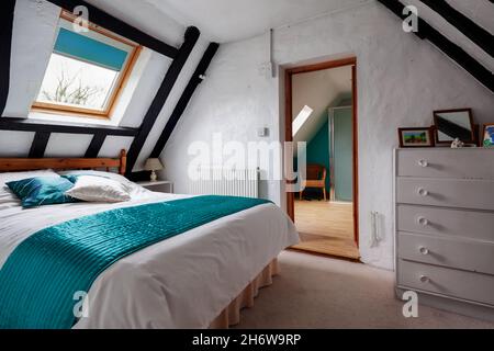 Kedington, Suffolk, November 19 2019: Bedroom in very old traditional British cottage with an abundance of exposed timbers and door leading to ensuite Stock Photo