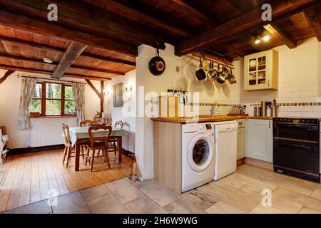 Kedington, Suffolk, November 19 2019: Heavily beamed kitchen and breakfast area with low ceiling and fitted cupboards inside traditional cottage. Stock Photo