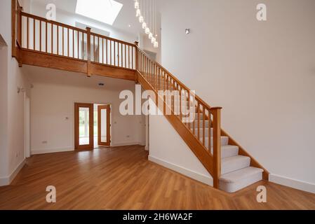Clavering, England -  April 6 2020: New Home entrance and reception hall with wooden floor and carpeted oak staircase rising to first floor landing Stock Photo