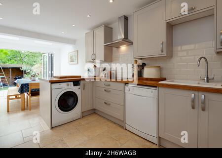 Cambridge, England - August 15 2019: Refitted kitchen with built in appliances inside Victorian era British home with dining area in background Stock Photo