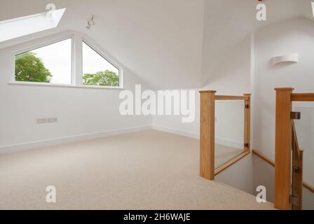 Cambridge, England - July 31 2019: Empty attic loft room within renovated home with natural wood staircase Stock Photo
