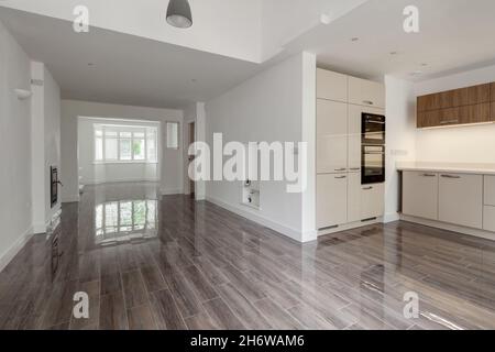 Cambridge, England - July 31 2019: Open Plan lounge and kitchen area in renovated vacant home with fitted units, built in appliances and ceramic floor Stock Photo