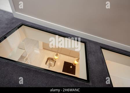 Cambridge, England - August 16 2019: Modern first floor landing area in renovated vacant house with unusual glass floor looking down into kitchen Stock Photo