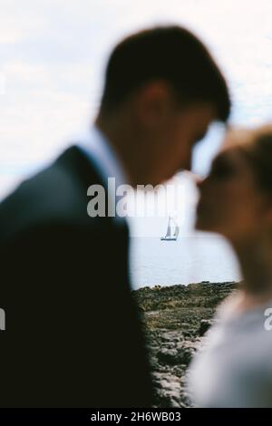 Silhouettes of almost kissing newlyweds on the background of a white sailing yacht in the open sea Stock Photo