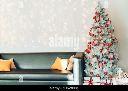White decorated christmas tree with gift boxes standing next to the sofa Stock Photo