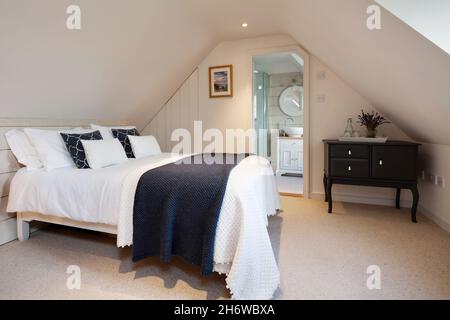 Calford Green, Suffolk, England - January 17 2020: Loft attic space bedroom with sloping ceiling bed and ensuite washroom shower room. Stock Photo