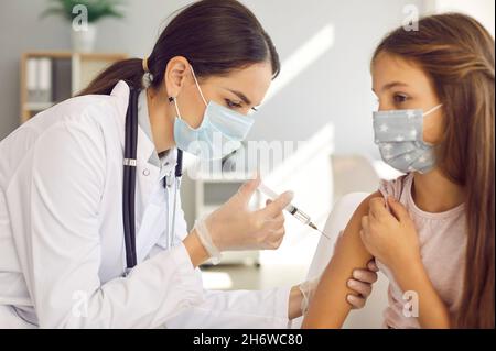 Nurse or doctor at a vaccination center giving a Covid 19 injection to a little child Stock Photo