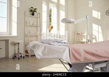 Empty interior of spa room or beauty salon with massage table and magnifying lamp Stock Photo