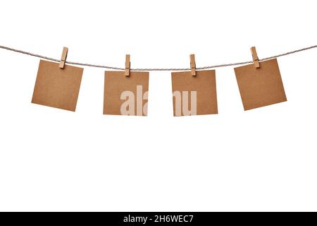Four craft paper blank notes hanging on the rope with wooden clothespins isolated on white background Stock Photo