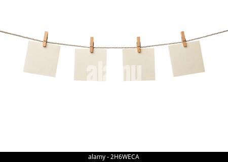 Four old paper blank notes hanging on the rope with wooden clothespins isolated on white background Stock Photo
