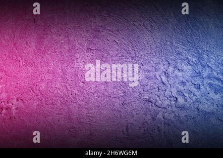 Black rough concrete wall background with neon lights and glowing lights. Lighting effect pink purple and blue on empty cement wall. Stock Photo