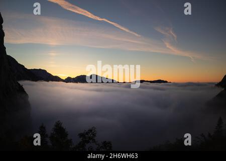 Sunrise on top of a mountain with view into misty valley with fog. Stock Photo