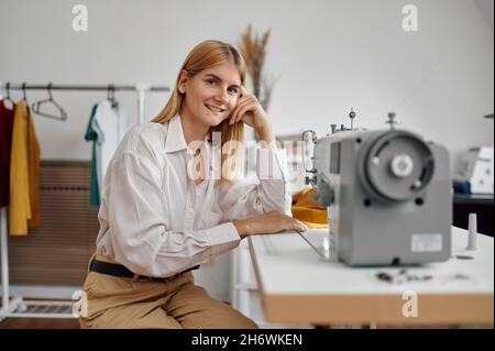 Seamstress works on sewing machine at workplace Stock Photo