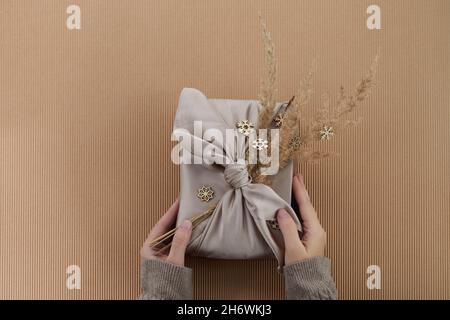 Zero waste Christmas flat lay. Hands holding simple christmas gift in furoshiki style. Plastic free sustainable lifestyle Stock Photo