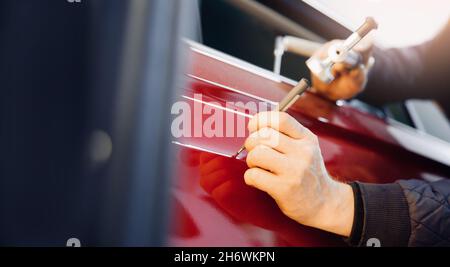 Master auto mechanic removal of dents defects without painting on car body on service station. Stock Photo