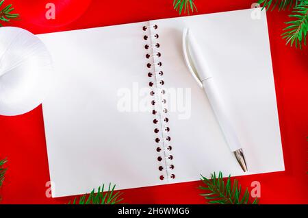 Green fir branches with an open notebook lie on a red background. Stock Photo