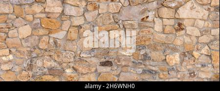 Coarse wall made of light brown natural stones in close-up Stock Photo