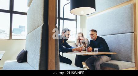 business colleagues using a smartphone during an important meeting. Three businesspeople working together in a modern co-working space. Team of divers Stock Photo