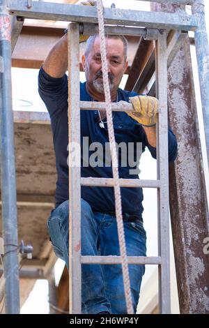 construction worker climbed on a ladder to repair the wall. Stock Photo