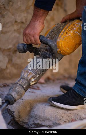 construction site worker with drilling machine removing the ground. Stock Photo