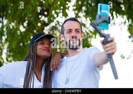 two friends of different ethnicities taking a selfie with the mobile Stock Photo