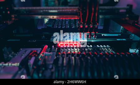 SMT Machine makes pick and place process with Circuit Board using Automated Robotic Arm. Assembling of system board components by robotic hand. Stock Photo