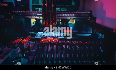 Automatic CNC machine Work: Assemble of system board elements by robotic hand. Technology for the precise installation of semiconductors and electronic components for the production of chips. Stock Photo