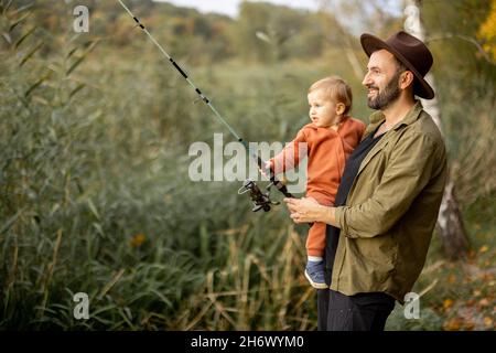 Such a small fish. Father and son stretching a fishing rod with