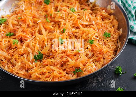Stewed cabbage on the  dark background in rustic style. Stock Photo