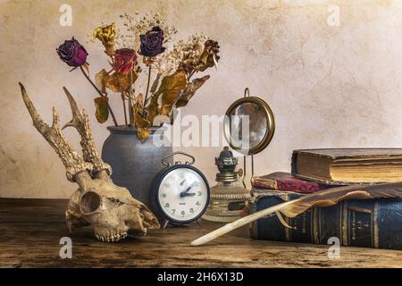 Still life expressing the passage of time with old vintage books, a kerosene lamp, a bouquet of flowers and a deer skull. Stock Photo