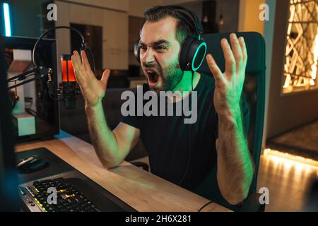 Angry devastated young man gamer wearing headphones lost a game on ...