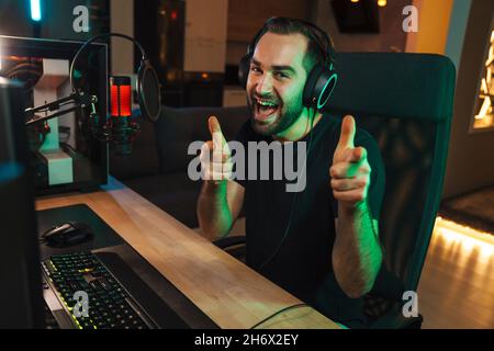 Premium Photo  Streamer man talking with multiple players into headphones  and winning video games competition. professional gamer streaming online  videogames with new graphics on powerful computer from gaming room