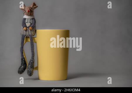 Yellow coffee or tea cup on neutral background and two toy mouses Stock Photo