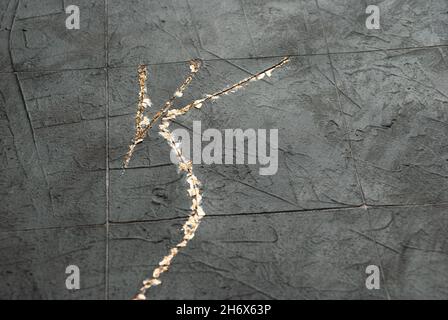 Putty dark gray background under the tiles in the style of kintsugi with black  slate board Stock Photo