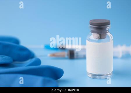 Medical glass bottle with copy space, on a blue background with syringes. Selective focus. Medical vial for injection with a syringe. Stock Photo