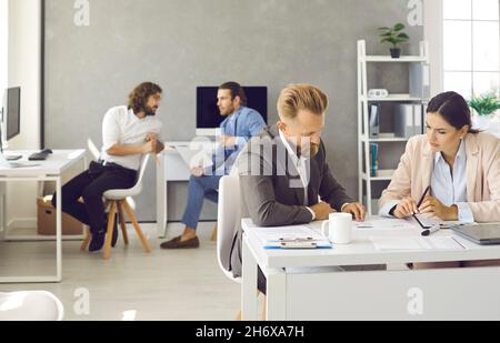 Group of smart successful business people working and communicating together in coworking office. Stock Photo