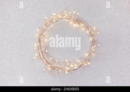 Flat lay top view, Christmas, wedding background circle shape border frame, light garland on glitter texture, metallic silver bright paper background. Stock Photo