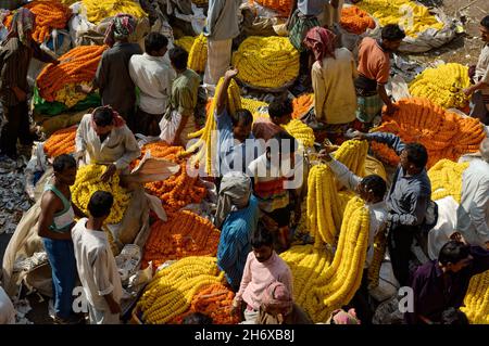 Traders in the Howrah flower market with marigolds and puja offerings, Kolkata, India Stock Photo