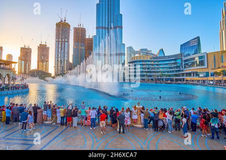 DUBAI, UAE - MARCH 3, 2020: Crowd of people watches Dubai Fountain show from the viewing platform of Souk Al Bahar bridge over Burj Khalifa lake, on M