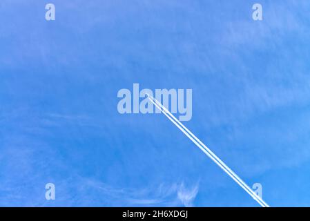 High flying passenger jet aircraft causing a white contrail against a blue sky Stock Photo