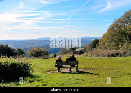 An elderly couple enjoying the sunny autumn day seated on a bench on top of the North Downs at Newlands Corner near Guildford Surrey England UK Stock Photo