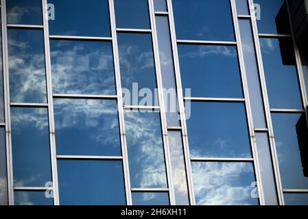 blue sky and clouds reflected from abstract glass windows in alternating shapes and tints Stock Photo
