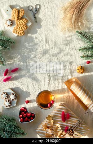 Xmas flat lay on off white textile, text space. Wintertime holiday background. Gift box wrapped in craft brown paper. Natural dry oak and bunny tail Stock Photo