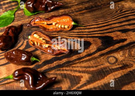 Chili pepper on wooden background.Extra hot chili. Naga Bhut Jolokia Chocolate. Exotic spices. Hot ingredients for food. Stock Photo