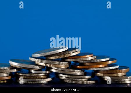 Various coins shown on blue background. The surface on which these coins are placed is dark blue. Stock Photo