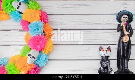 Day of the Dead background - White painted plank background with colorful skull wreath on one side and Mexican skeleton mariachi player and dog with c Stock Photo