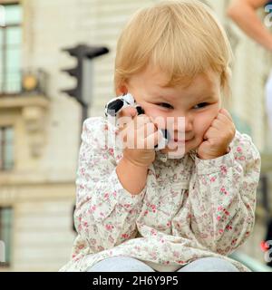 Angry blond baby girl with a toy in hands Stock Photo