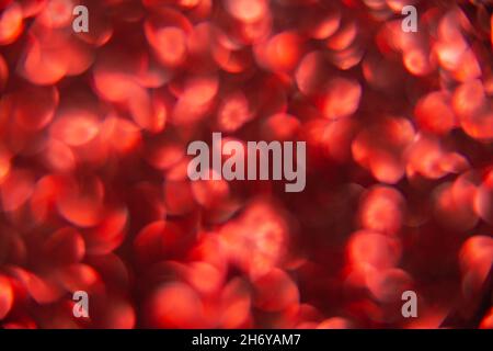 Texture created from oval red objects. The effect was obtained by photographing the glitter surface in a macro scale without focusing. Stock Photo